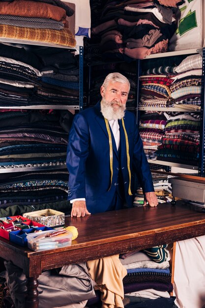 Retrato de um designer de moda masculina sênior em sua loja de roupas