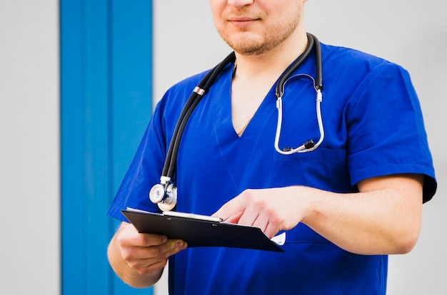 Retrato, de, um, doutor masculino, com, estetoscópio, ao redor, pescoço, examinando, a, relatório médico