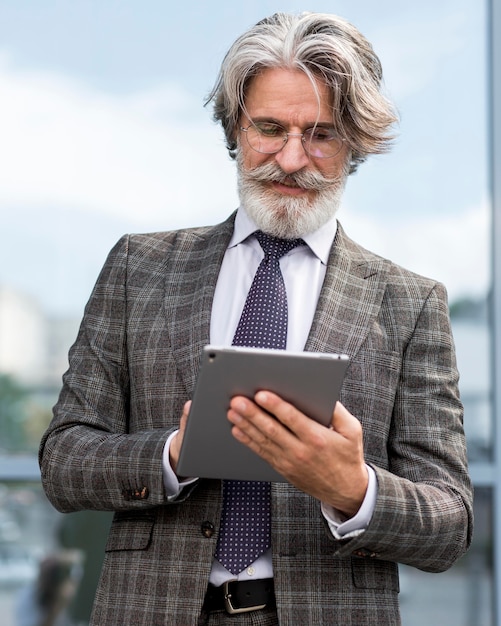 Foto grátis retrato de um elegante tablet de navegação masculino maduro