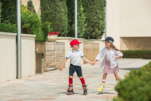 Retrato de um encantador casal adolescente patinando juntos de patins no parque. Menino e menina adolescentes caucasianos