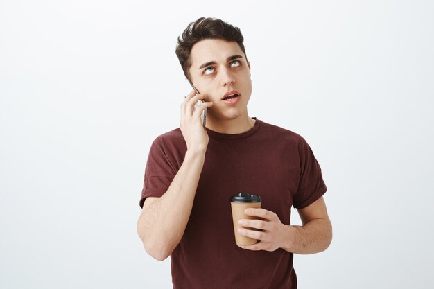 Retrato de um europeu irritado e puto com uma camiseta vermelha falando ao telefone