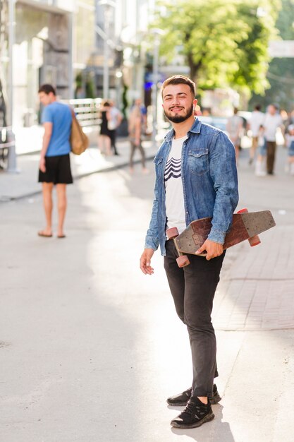 Retrato, de, um, feliz, homem jovem, com, skateboard