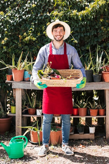 Retrato, de, um, feliz, jovem, macho, jardineiro, segurando, potted, plantas, em, a, cesta