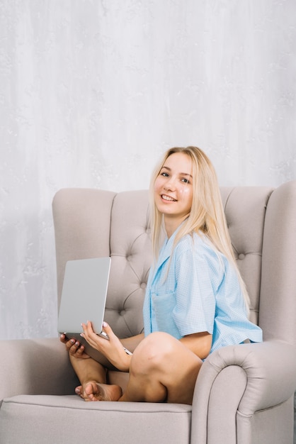 Retrato, de, um, feliz, mulher senta-se poltrona, com, laptop