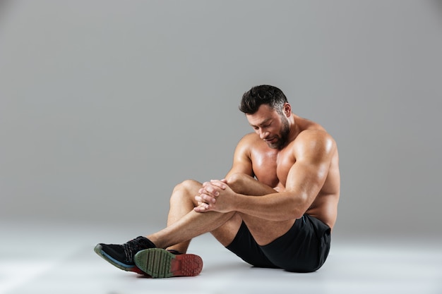 Retrato de um fisiculturista masculino sem camisa forte cansado descansando