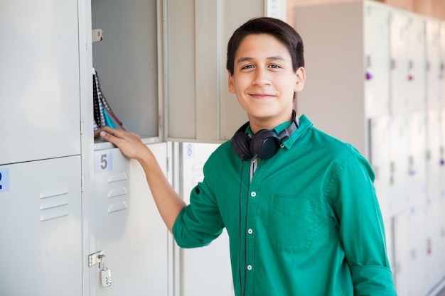 Retrato de um garoto hispânico atraente ao lado de alguns armários e usando fones de ouvido