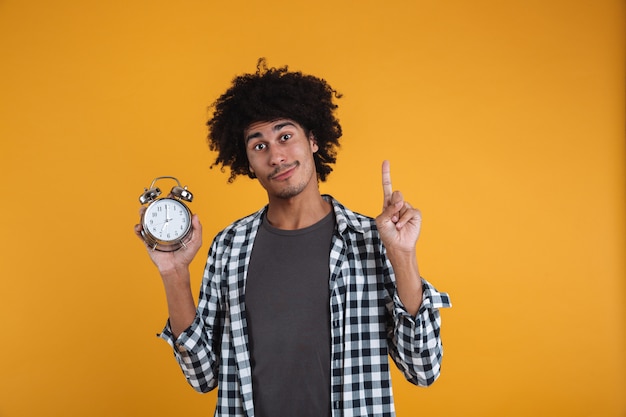 Foto grátis retrato de um homem africano casual sorridente, mostrando o despertador