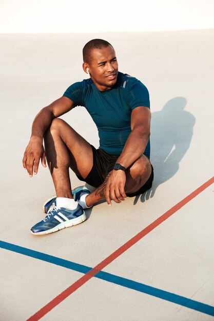 Retrato de um homem Africano fitness sorridente em fones de ouvido descansando