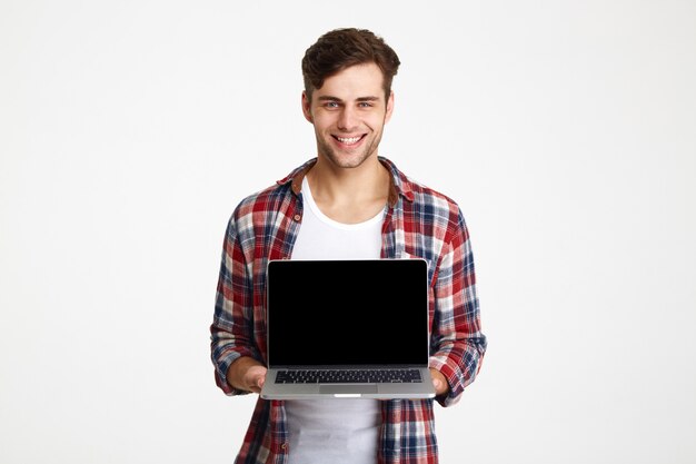 Retrato de um homem alegre feliz, mostrando o laptop de tela em branco
