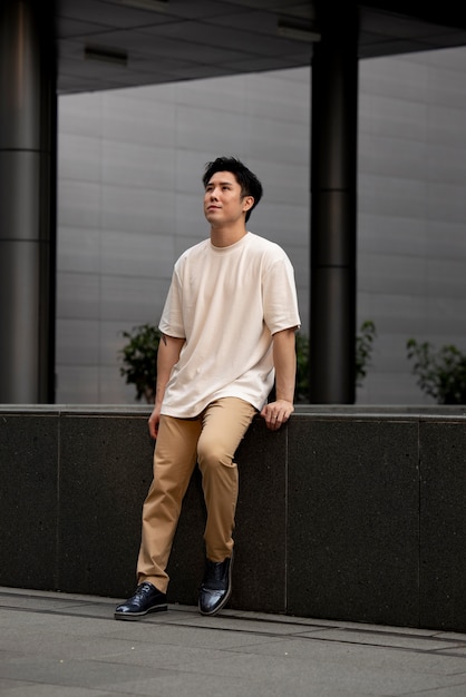 Retrato de um homem asiático bonito posando ao ar livre na cidade