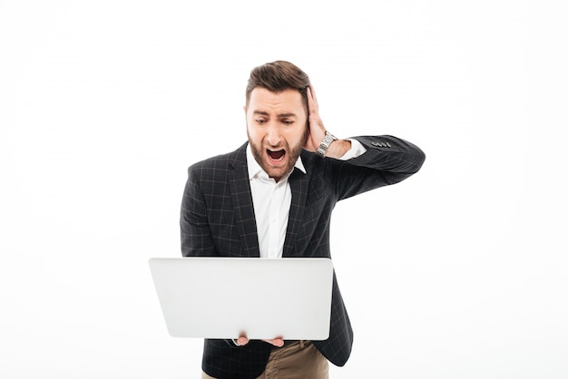 Foto grátis retrato de um homem barbudo com raiva, segurando o computador portátil