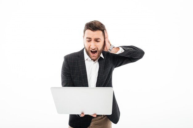 Retrato de um homem barbudo com raiva, segurando o computador portátil