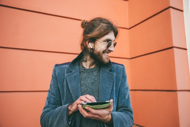 Retrato de um homem barbudo sorridente, vestido com casaco