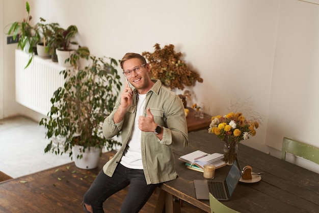 Retrato de um homem bonito e feliz em um escritório. Um cara senta-se em um espaço de coworking olhando para a câmera sorrindo.