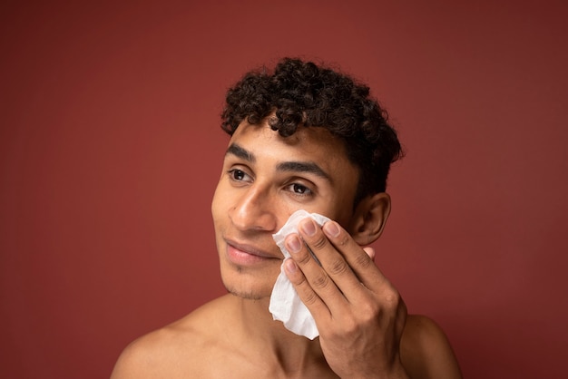 Retrato de um homem bonito limpando o rosto com um lenço de papel