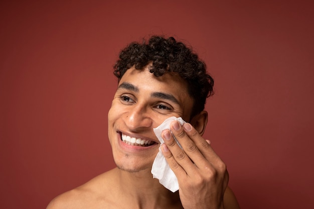 Retrato de um homem bonito limpando o rosto com um lenço de papel