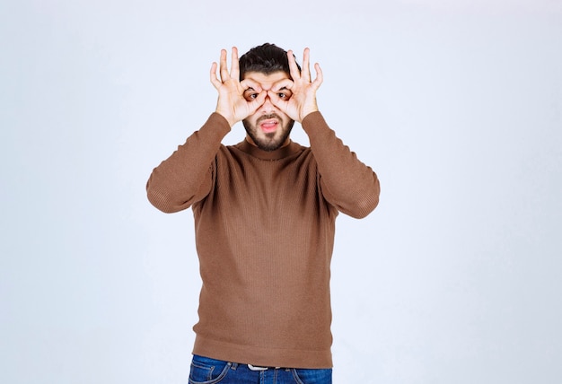 Retrato de um homem bonito olhando por entre os dedos