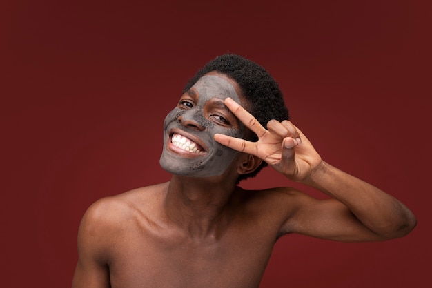 Foto grátis retrato de um homem bonito sorrindo com máscara de carvão no rosto