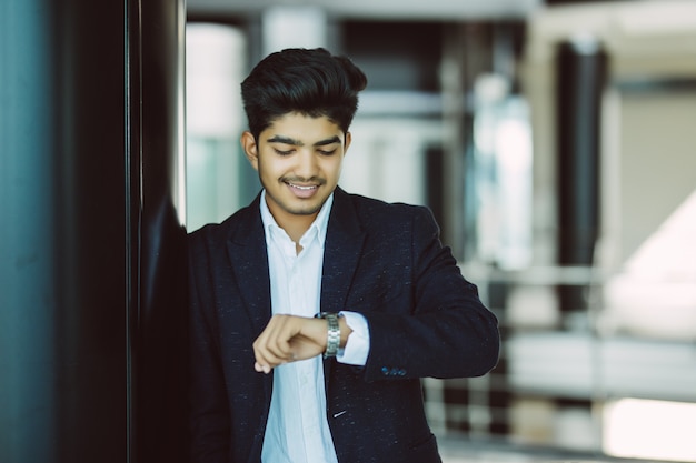 Retrato de um homem de negócios jovem assistindo relógio no escritório