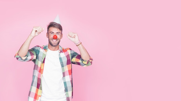 Retrato de um homem feliz com nariz de palhaço no fundo rosa