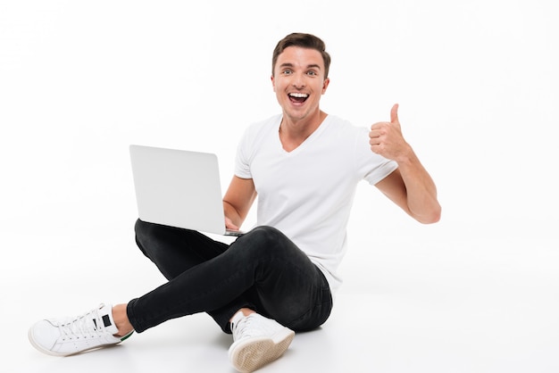 Retrato de um homem feliz e animado, segurando o computador portátil