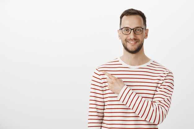 Retrato de um homem feliz e satisfeito com as cerdas em óculos da moda e um pulôver listrado