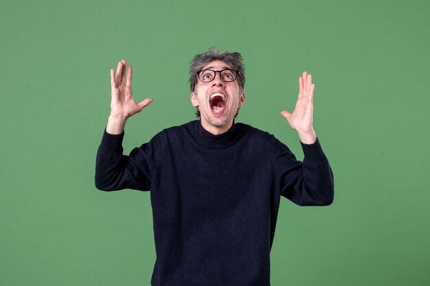 Retrato de um homem gênio vestido casualmente em estúdio, tiro olhando para cima na parede verde