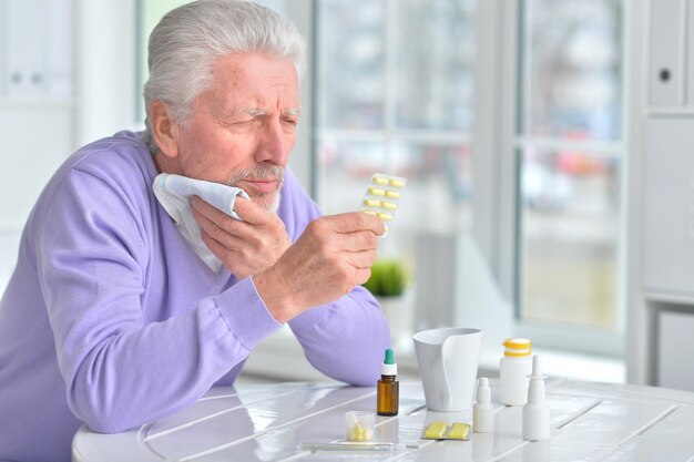 Retrato de um homem idoso doente tomando remédio