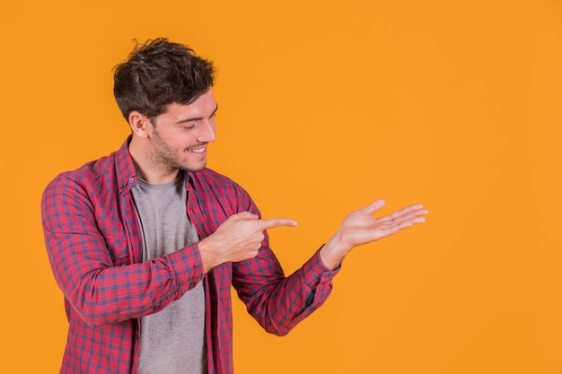 Retrato, de, um, homem jovem, apontar, seu, dedo, mão, contra, um, fundo laranja