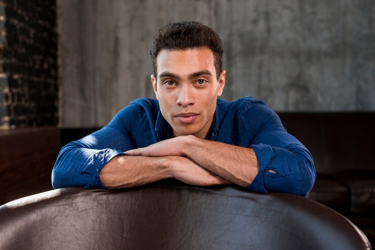 Foto grátis retrato, de, um, homem jovem, inclinar-se, borda, de, sofá, olhando câmera