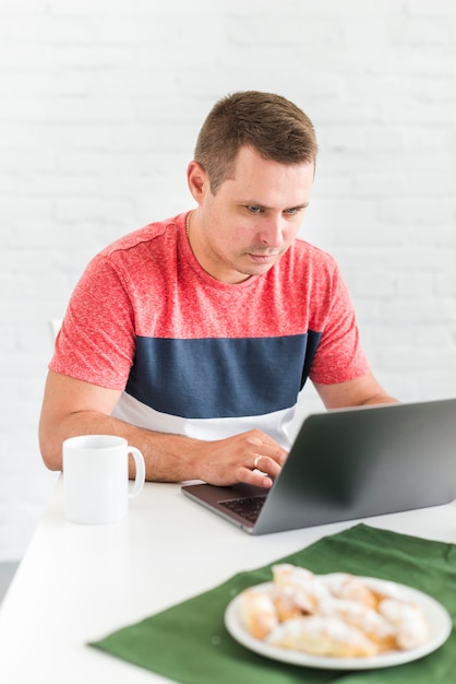 Retrato, de, um, homem jovem, usando computador portátil, escrivaninha