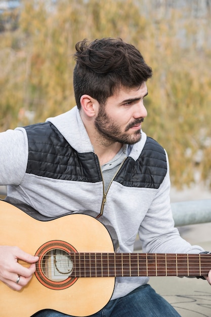 Foto grátis retrato, de, um, homem jovem, violão jogo, em, ao ar livre