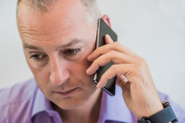 Retrato de um homem maduro preocupado falando com telefone inteligente