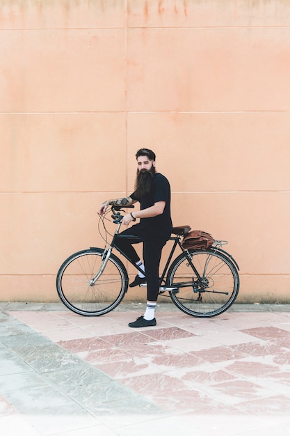 Retrato, de, um, homem moderno, ficar, com, seu, bicicleta, contra, parede