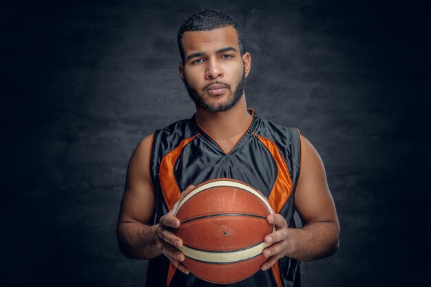 Retrato de um homem negro barbudo detém uma bola de basquete.