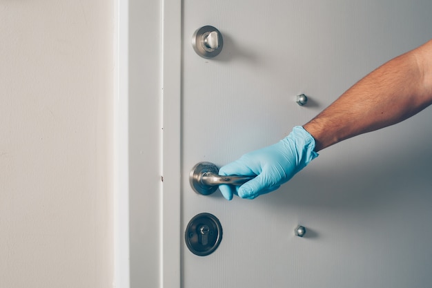 Retrato de um homem no quarto, abrindo a porta com as mãos nas luvas