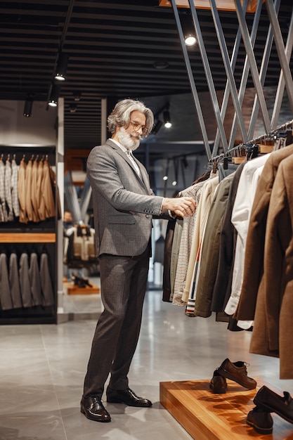 Retrato de um homem rico e maduro. Sênior visitando uma boutique de moda. Masculino compre um novo traje exclusivo.