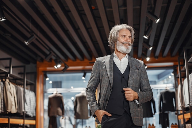 Foto grátis retrato de um homem rico e maduro. sênior visitando uma boutique de moda. masculino compre um novo traje exclusivo.