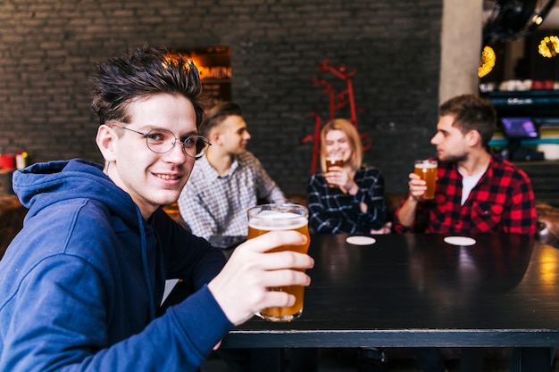 Retrato, de, um, homem, segurando, a, vidro cerveja, sentar-se, com, amigos