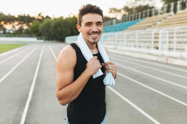 Retrato de um homem sorridente de fitness com toalha nos ombros