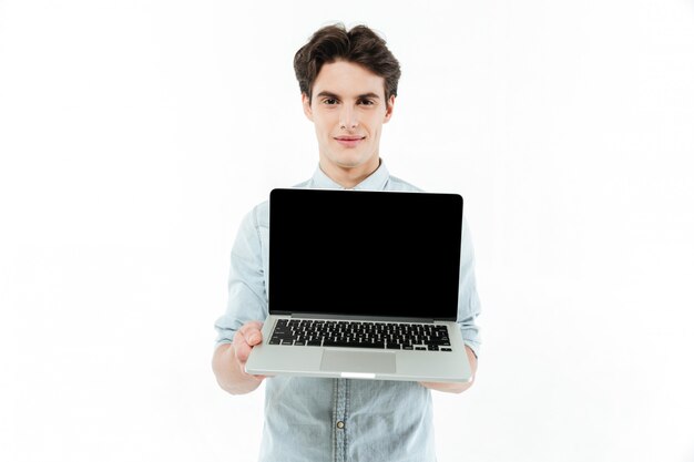 Retrato de um homem sorridente, mostrando o computador portátil de tela em branco