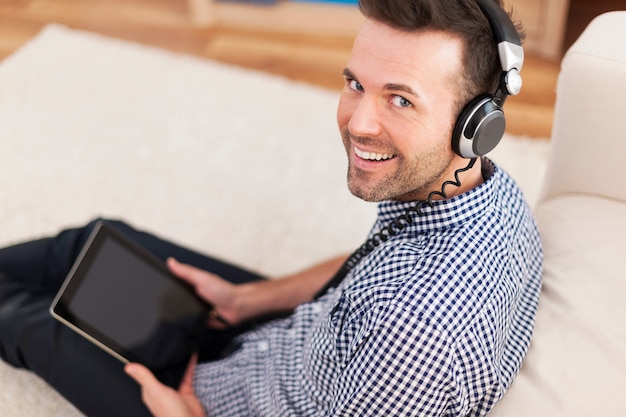 Retrato de um homem sorridente ouvindo música em casa