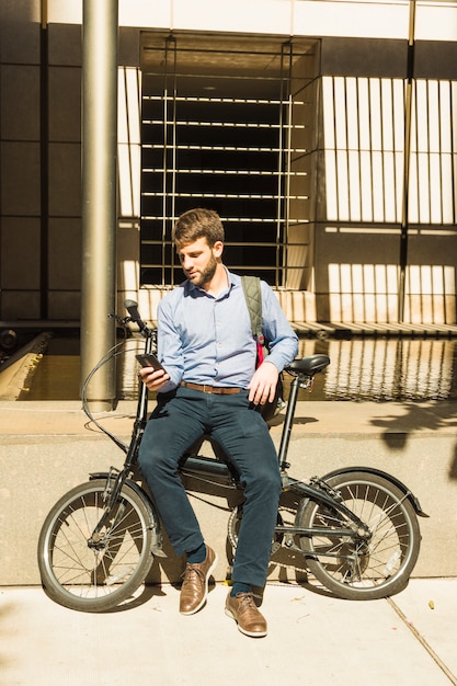 Retrato, de, um, homem usa telefone móvel, sentando, com, bicicleta