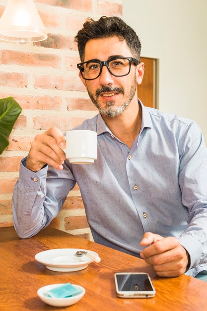 Retrato, de, um, homem, xícara café segurando, em, mão, com, telefone móvel, ligado, tabela