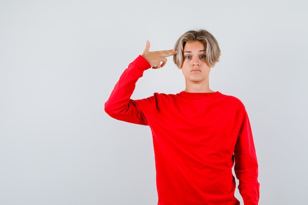 Retrato de um jovem adolescente mostrando um gesto suicida com um suéter vermelho e olhando confuso para a frente