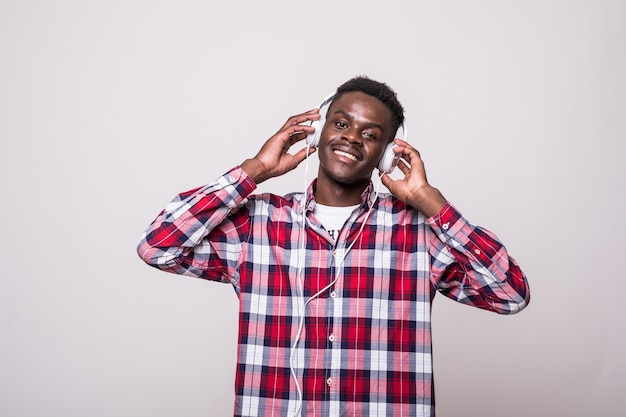 Retrato de um jovem afro-americano alegre ouvindo música com fones de ouvido e cantando isolado