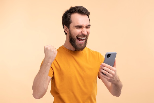 Retrato de um jovem animado olhando para seu smartphone