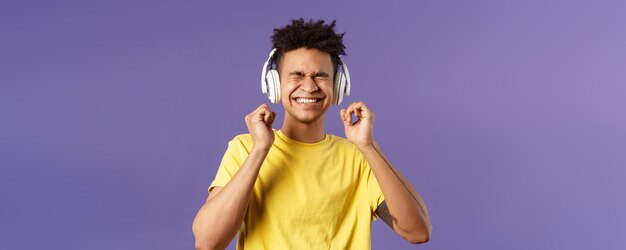 Retrato de um jovem animado satisfeito desfrutando de batidas incríveis de boa qualidade em fones de ouvido fecham os olhos a