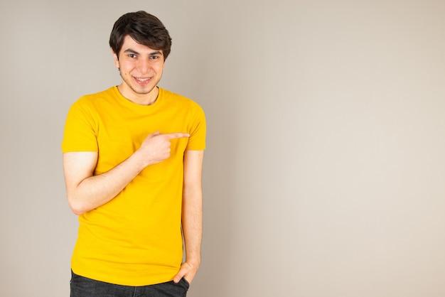 Foto grátis retrato de um jovem apontando com os dedos contra o cinza.