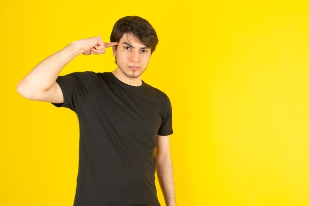 Retrato de um jovem apontando para o templo contra amarelo.